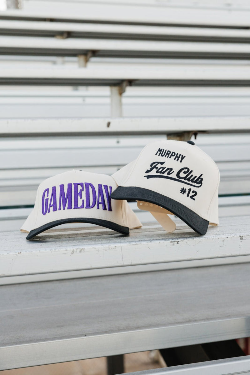 Bleacher scene with Embroidered Fan Club Vintage Trucker Hat beside a purple GAMEDAY cap.