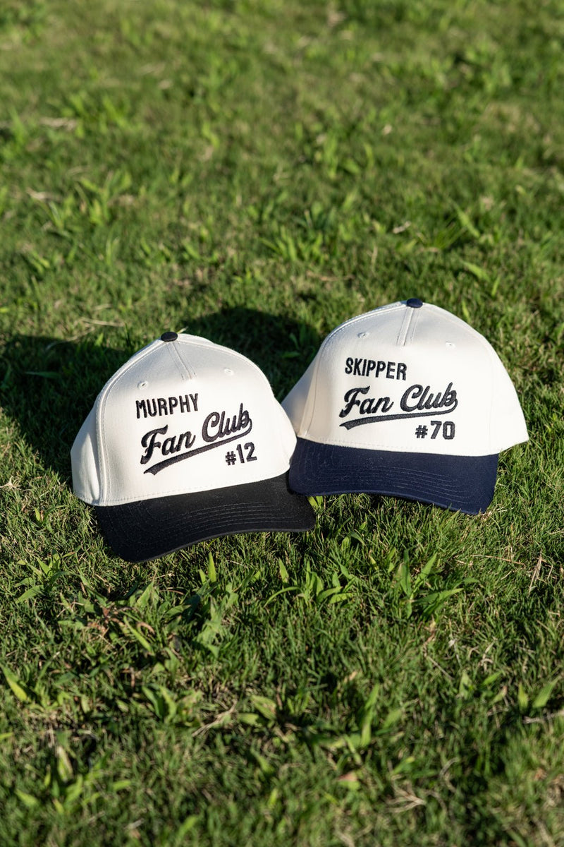 Two Embroidered Fan Club Vintage Trucker Hats on grass: “Murphy #12” and “Skipper #70.”