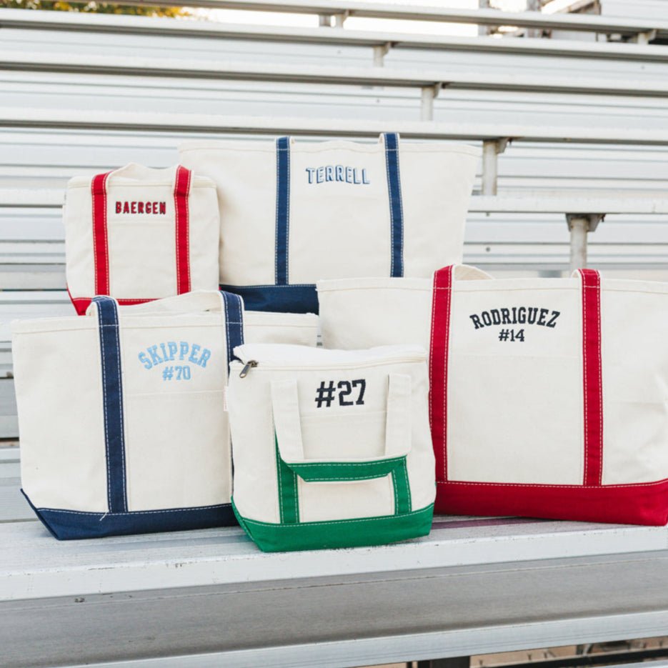 Three canvas totes with navy, red, and cream trim, embroidered with “MW,” “WALKUP #12,” or “EAGLES”