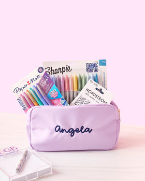 A purple nylon pouch is customized with a name and filled with pens and a gift card.