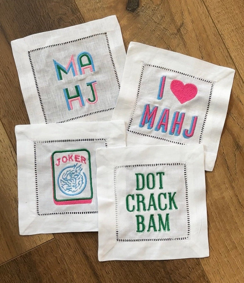 Set of four Embroidered Mahjong Cocktail Napkins featuring playful, colorful designs with sayings like “I ♥ MAHJ,” “DOT CRACK BAM,” and “JOKER” — the perfect game night accessory for Mahjong enthusiasts.