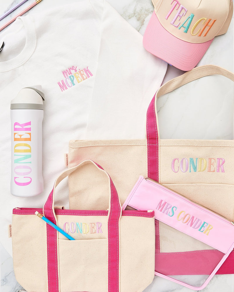 Styled teacher essentials flat lay – @PBANDJ4THGRADE x SWP embroidered natural canvas tote with hot-pink trim and multicolor “CONDER” monogram