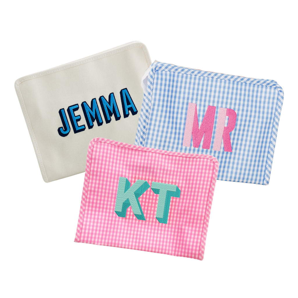 A solid cream, blue gingham, and a pink gingham pouch are customized with embroidered names and monograms.