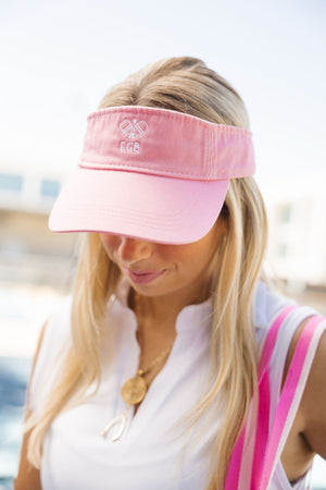A girl wears a pink visor with an embroidered pickleball motif and her initials