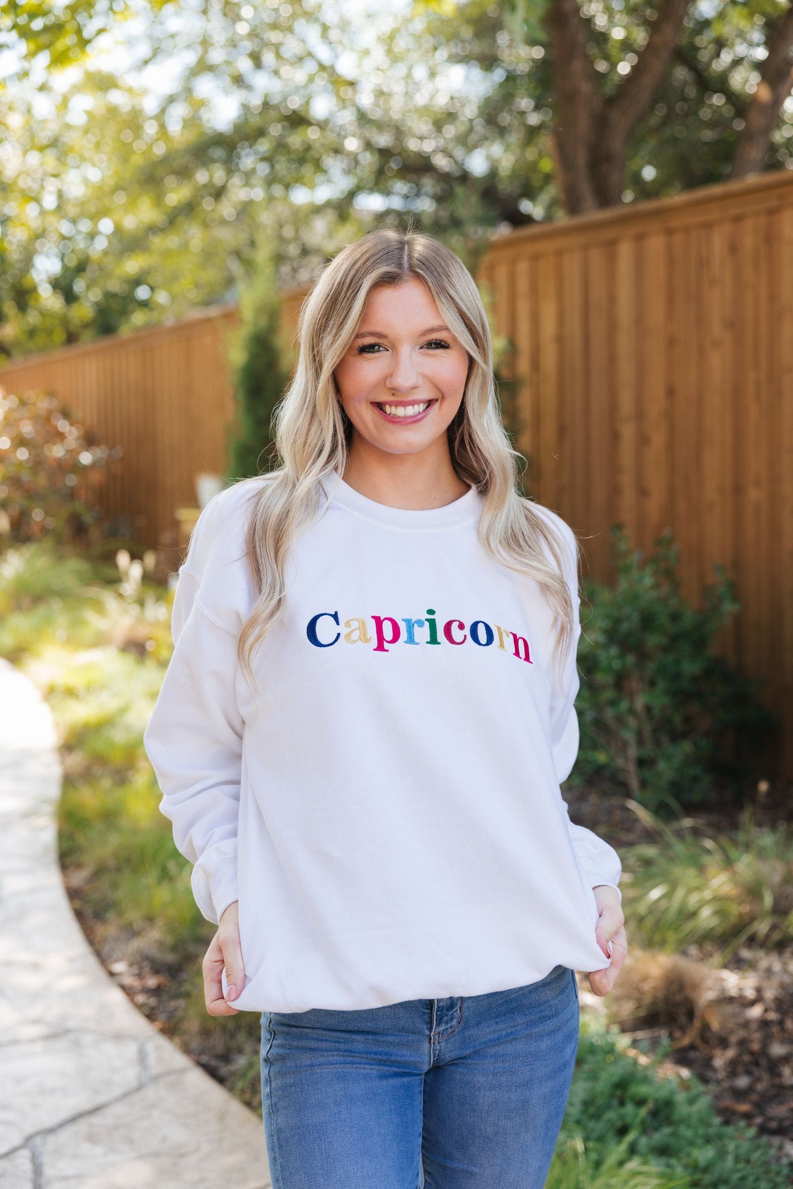 A white sweatshirt with embroidered multi-colored letters 