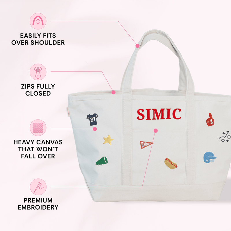 Natural canvas gameday tote with black trim embroidered "SIMIC" in red, with baseball-themed icon embroideries including a jersey, foam finger, star, and megaphone, shown with feature callouts for shoulder strap, zip closure, heavy canvas, and premium embroidery