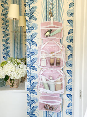 Hanging embroidered pink toiletry bag from Sprinkled With Pink, filled with beauty and skincare essentials.