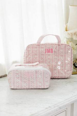 Pink striped monogrammed hanging toiletry bag set with wipeable finish, featuring two sizes displayed on marble counter.