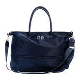 A navy blue nylon duffel bag with top handles, a detachable shoulder strap, and gold-tone hardware. The front features a zippered pocket and the initials 'CHS' in white embroidered lettering, set against a plain white background.