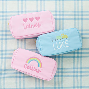 Personalized pouches in pastel colors featuring embroidered names 'Lainey,' 'Luke,' and 'Collins' 