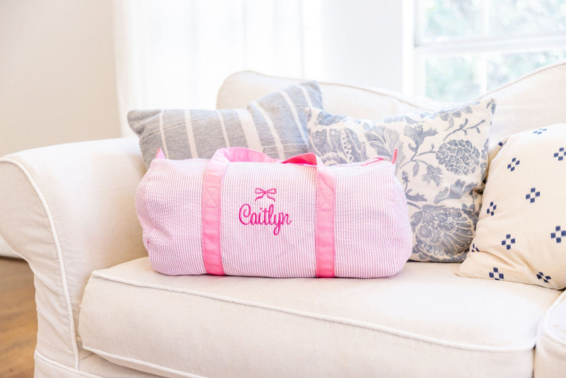 Pink striped duffel bag featuring matching pink handles.