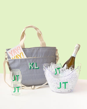A navy cooler tote is monogrammed and placed with a wide ice bucket and 3 green wine glasses.