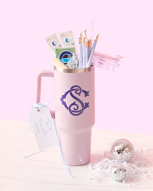 A purple monogrammed 40 ounce tumbler is filled with purple pencils and some gum.