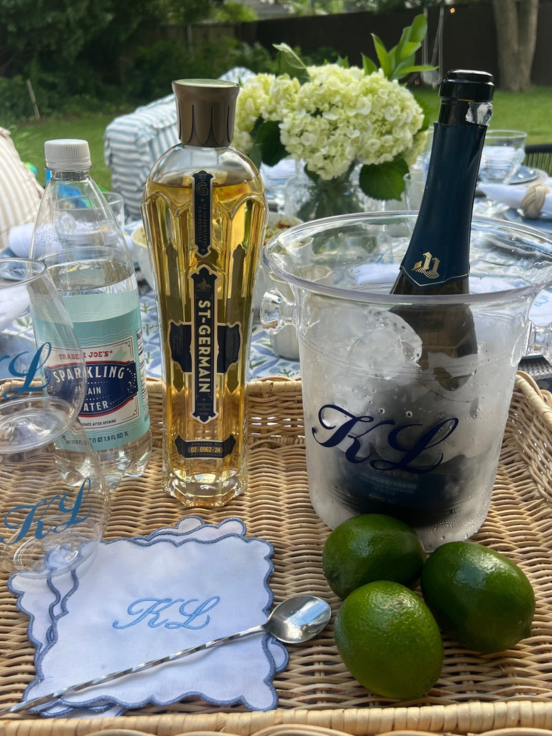 Chic outdoor cocktail bar setup featuring Sprinkled With Pink's Embroidered Monogram Scalloped Cocktail Napkins (Set of 4), personalized with a blue “KL” script and scalloped trim—perfectly styled alongside limes, monogrammed drinkware, and a matching ice bucket for a sophisticated summer gathering.