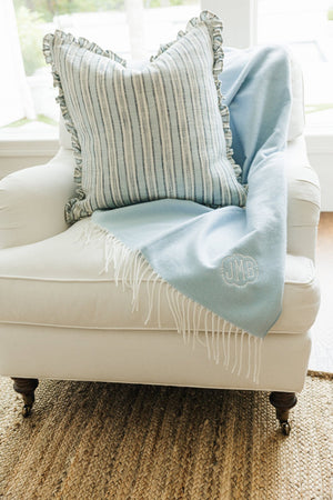 Light blue Monogrammed Woven Blanket with JMB embroidery draped on armchair with striped pillow.