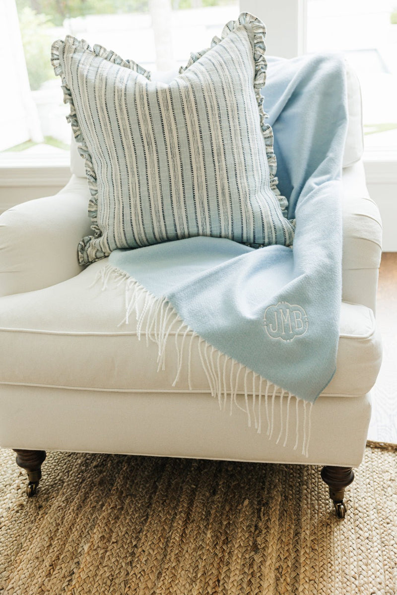 Light blue Monogrammed Woven Blanket with JMB embroidery draped on armchair with striped pillow.