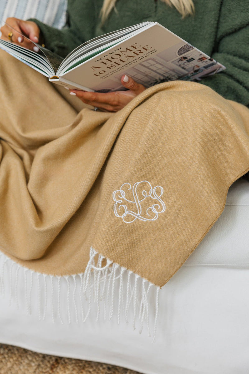 Camel Monogrammed Woven Blanket with white embroidered initials draped over sofa.