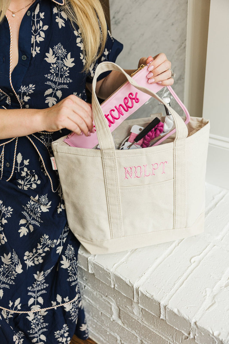 Woman holding a pink Needlepoint Canvas Project Tote with a matching pouch inside.