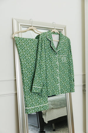 Green floral pajama set with monogrammed initials displayed on a hanger against a mirror.