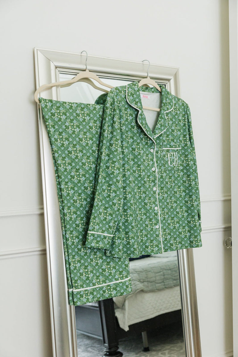 Green floral pajama set with monogrammed initials displayed on a hanger against a mirror.