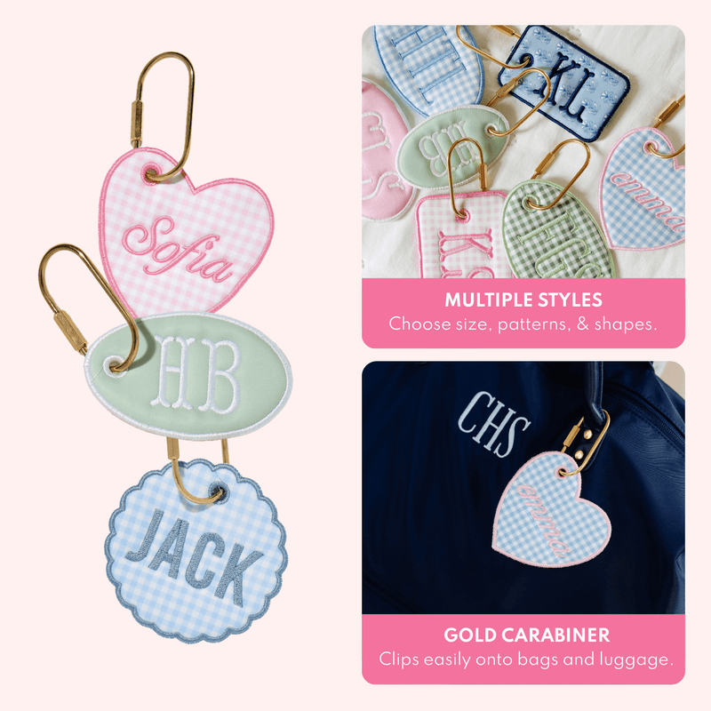 Close-up of assorted bag tags in multiple shapes and patterns, and a heart-shaped blue gingham bag tag embroidered 'emma' clipped to a navy duffel monogrammed 'CHS', with text describing multiple styles and a gold carabiner that clips onto bags and luggage.