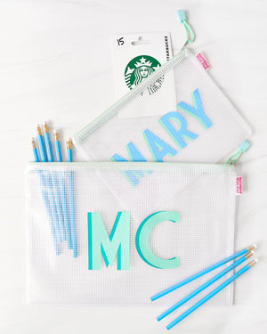 A small and a large pool bag with mint zippers are customized with monograms and filled with pencils and a gift card.