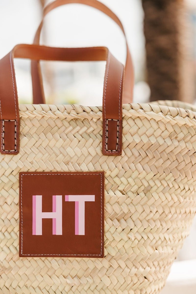 A straw tote is customized with a pink monogram