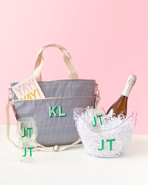 A navy cooler tote is monogrammed and placed with a wide ice bucket and 3 green wine glasses.