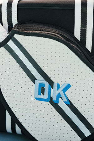 A black and silver striped pickleball bag is customized with a blue monogram.