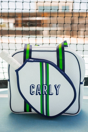 A green and navy striped pickleball bag is customized with an embroidered name on a pickleball court.