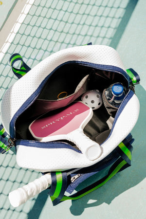A pickleball bag is opened to to show a paddle, a wiffle ball, and a water bottle inside.