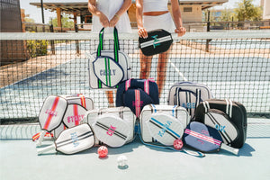 A group of pickleball bags and paddle covers that have been customized with monograms and names in different colors.