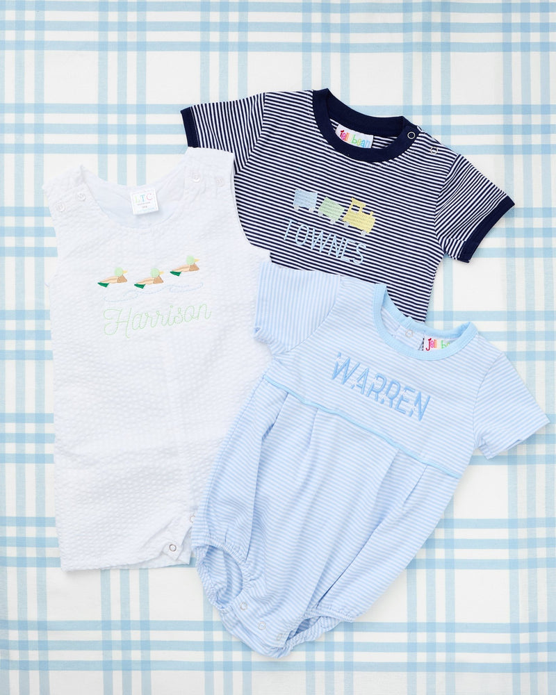 Short Sleeve Striped Bubbles from Rainey Laine featuring personalized designs—light blue striped bubble with a green tractor trailer motif and name ‘Henry,’ and navy striped bubble with yellow construction truck motif and name ‘Townes,’ both laid out on a soft blue plaid background.
