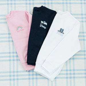 Three personalized children's sweaters featuring unique embroidered designs
