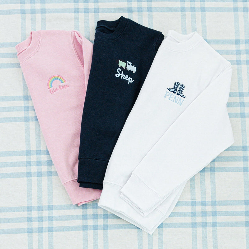 Three personalized children's sweaters featuring unique embroidered designs