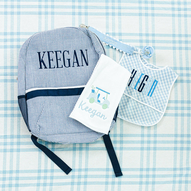 Personalized baby set for Keegan, including a striped backpack, bib, towel, and pacifier clip