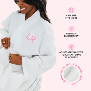 Woman wearing a white waffle knit robe embroidered 'LR' in pink, with text describing one size fits most, premium embroidery, an adjustable waist tie, and comfortable cozy high-quality waffle knit.
