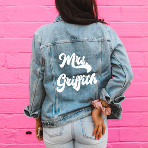 A woman wears a custom denim jacket with retro script that reads "Mrs. Griffith"