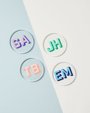 Four coasters are laid out showing off their vibrant monograms in different colors.