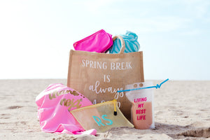 A customized spring break tote filled with products sits on a beach