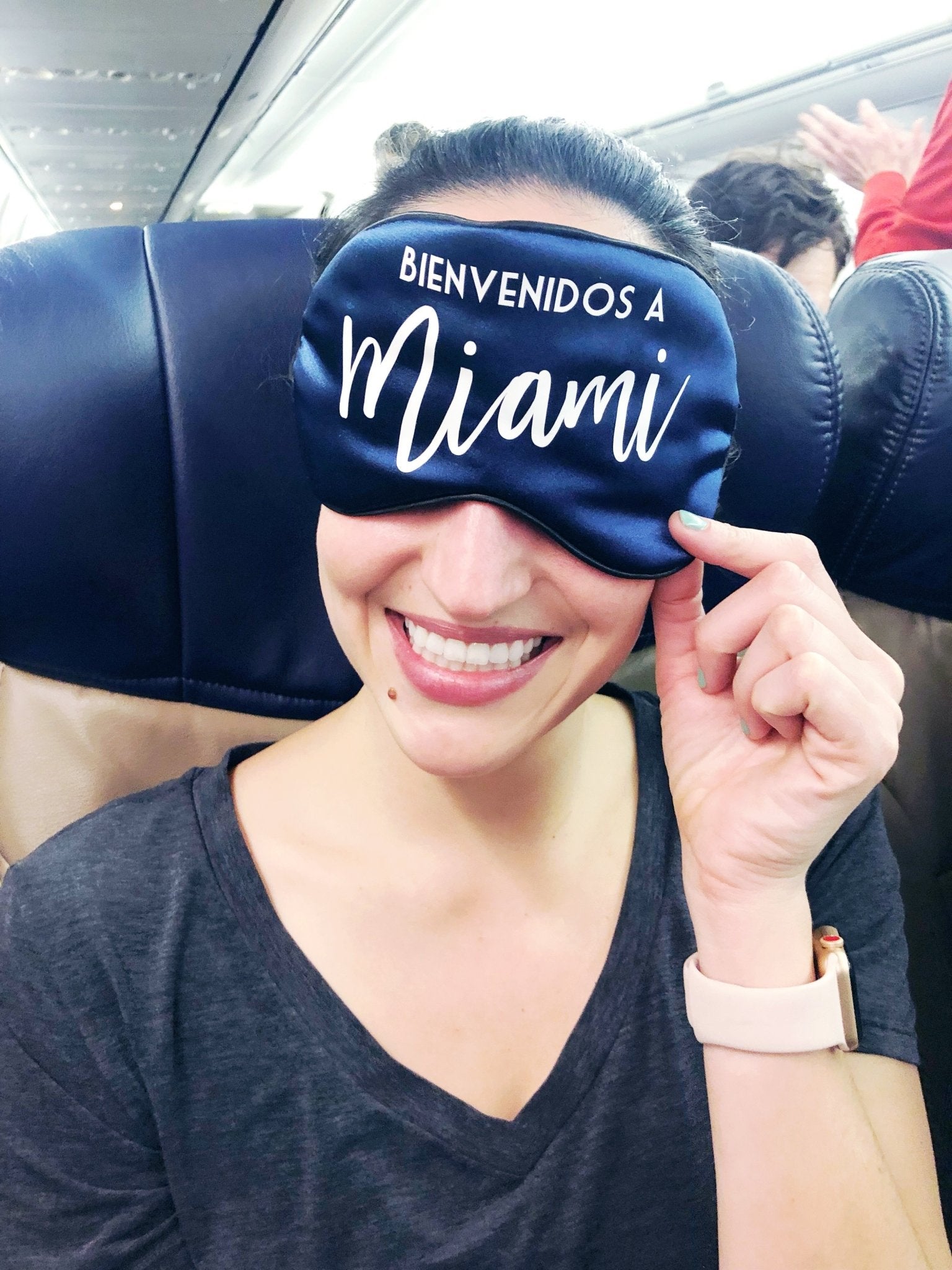 A navy colored sleep mask reads "bienvenidos a Miami"
