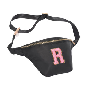 A black nylon fanny pack is customized with a pink patch letter