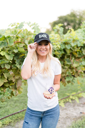 A blonde wears a baseball hat that says "BABE"