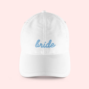 A white baseball hat customized to read "bride" in blue script