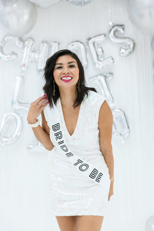 A bride smiles while wearing her custom bride-to-be sash