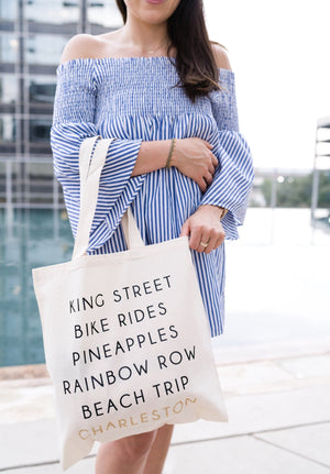 A woman in a blue dress carries our custom Charleston bag