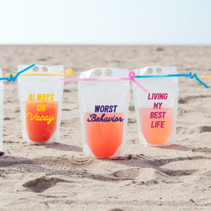 3 party pouches with fun phrases like "Always on Vacay" sit in the sand at the beach.