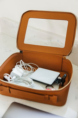 A tan leather case is filled with cords and headphones.