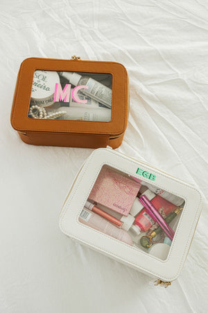 A tan and white clear leather case are filled with toiletries and customized with monograms.