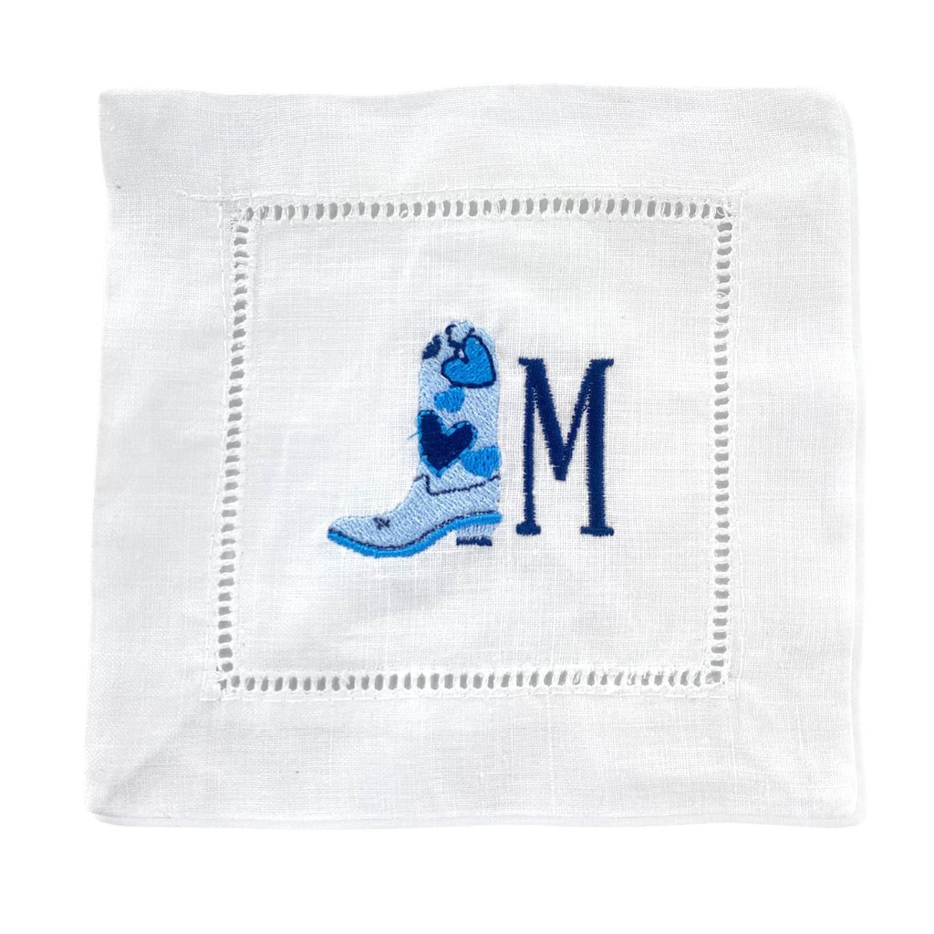 A cocktail napkin with an embroidered blue cowboy boot and navy initial.